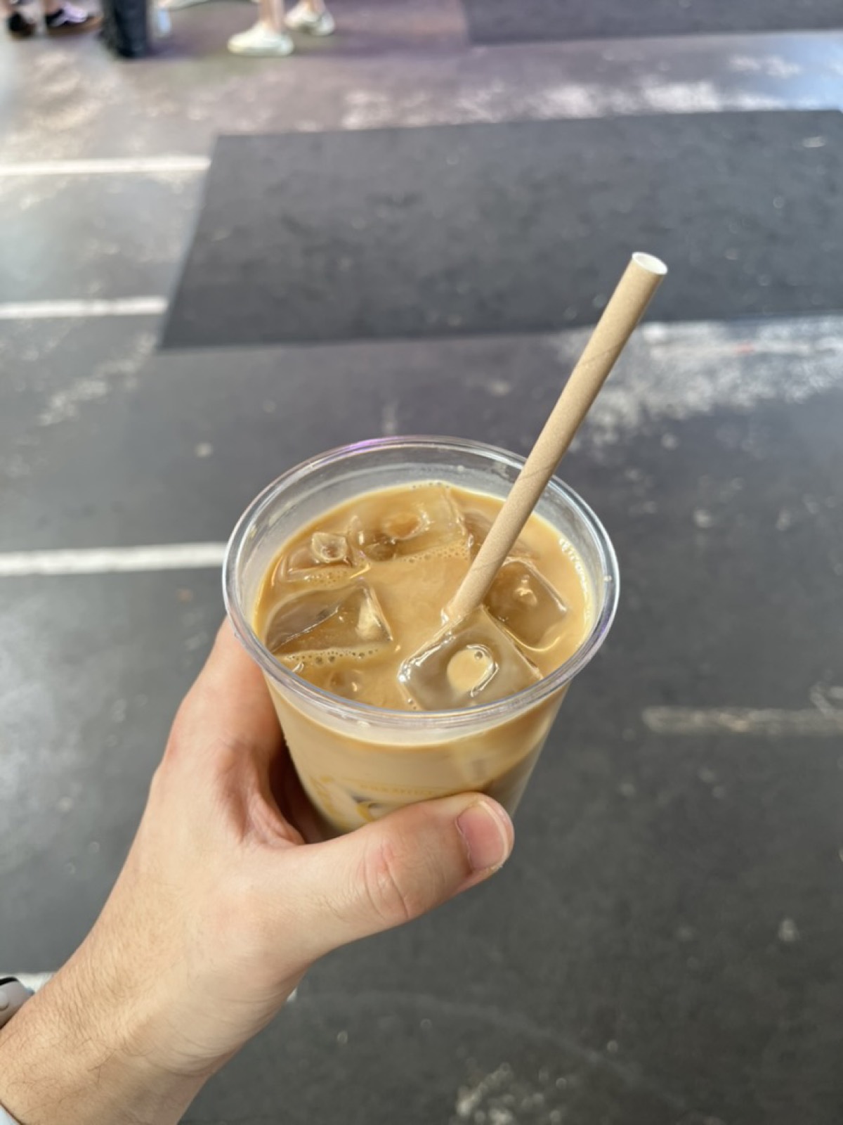 Copo de café gelado na mão, no pátio do evento