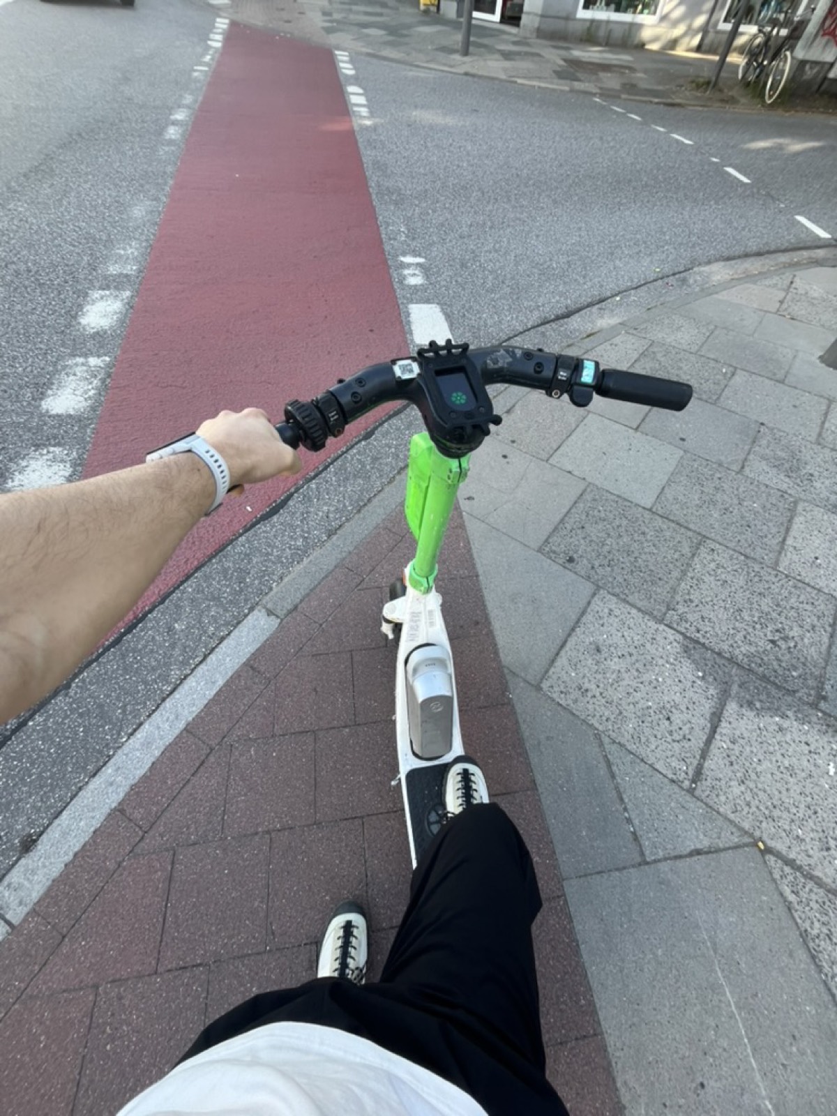 Foto em primeira pessoa guiando um patinete elétrico numa ciclovia vermelha em Hamburgo